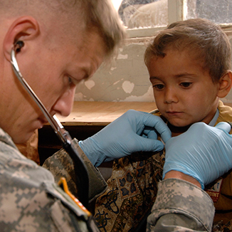 A military physician examines a child. A military physician examines a child.