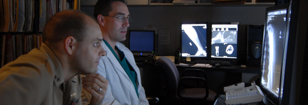 Two military medical professionals evaluate an X-ray.