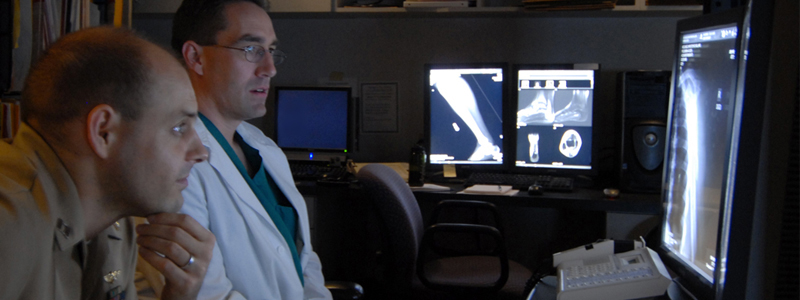Two military medical professionals evaluate an X-ray.