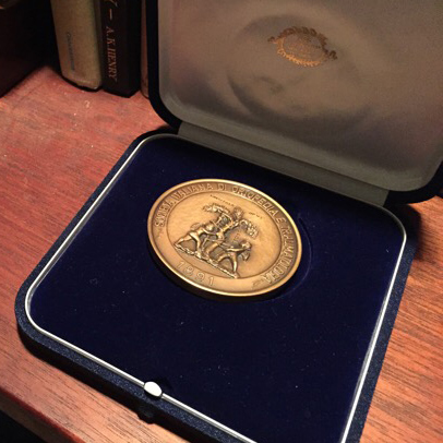 gold award medal in case on bookshelf 