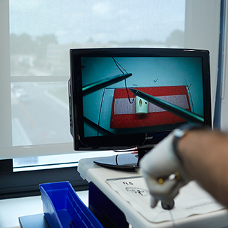 A military physician uses remote instruments in a simulation.