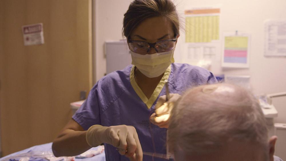 Josephine applying sutures to patient's shoulder 