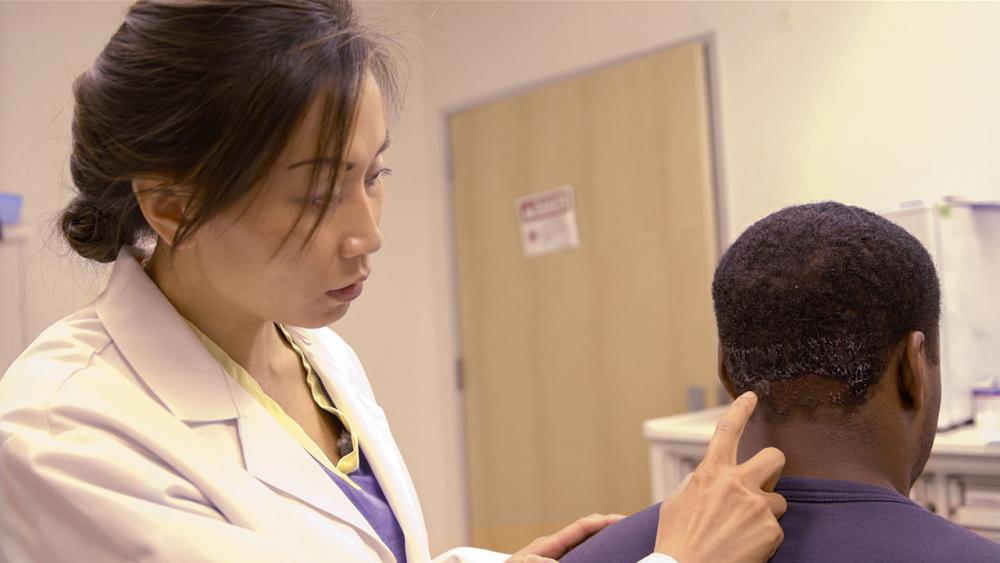 Josephine pointing to patient's pseudofolliculitis